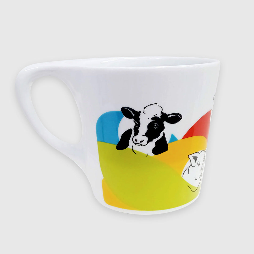 White ceramic mug with handle facing the left and a cow illustration in black facing front. A pig illustration is partly visible on the right side of the mug. There are brightly colored bands flowing under the animal heads like waves. All of the animal illustrations on the mug are in black and of the animals' heads and upper bodies.