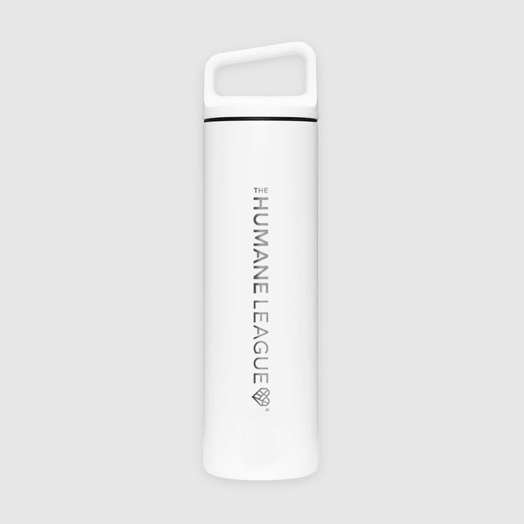 A white version of the metal water bottle with a slanted handle top. The Humane League logo with geometric heart icon is engraved horizontally on the length of the bottle.