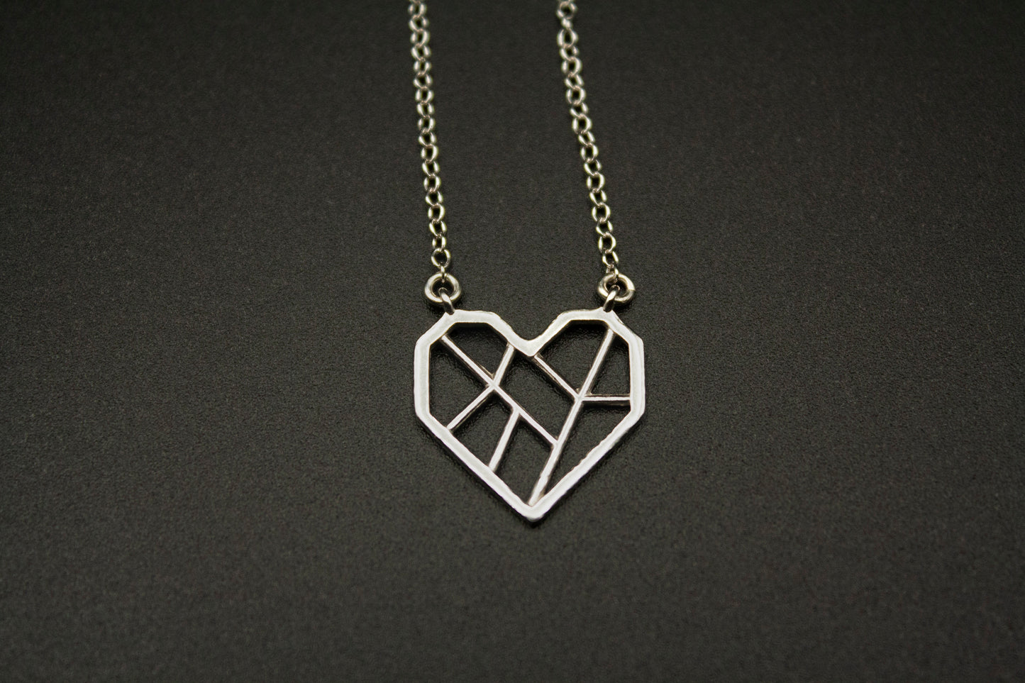 Photograph of the silver necklace against a black background.