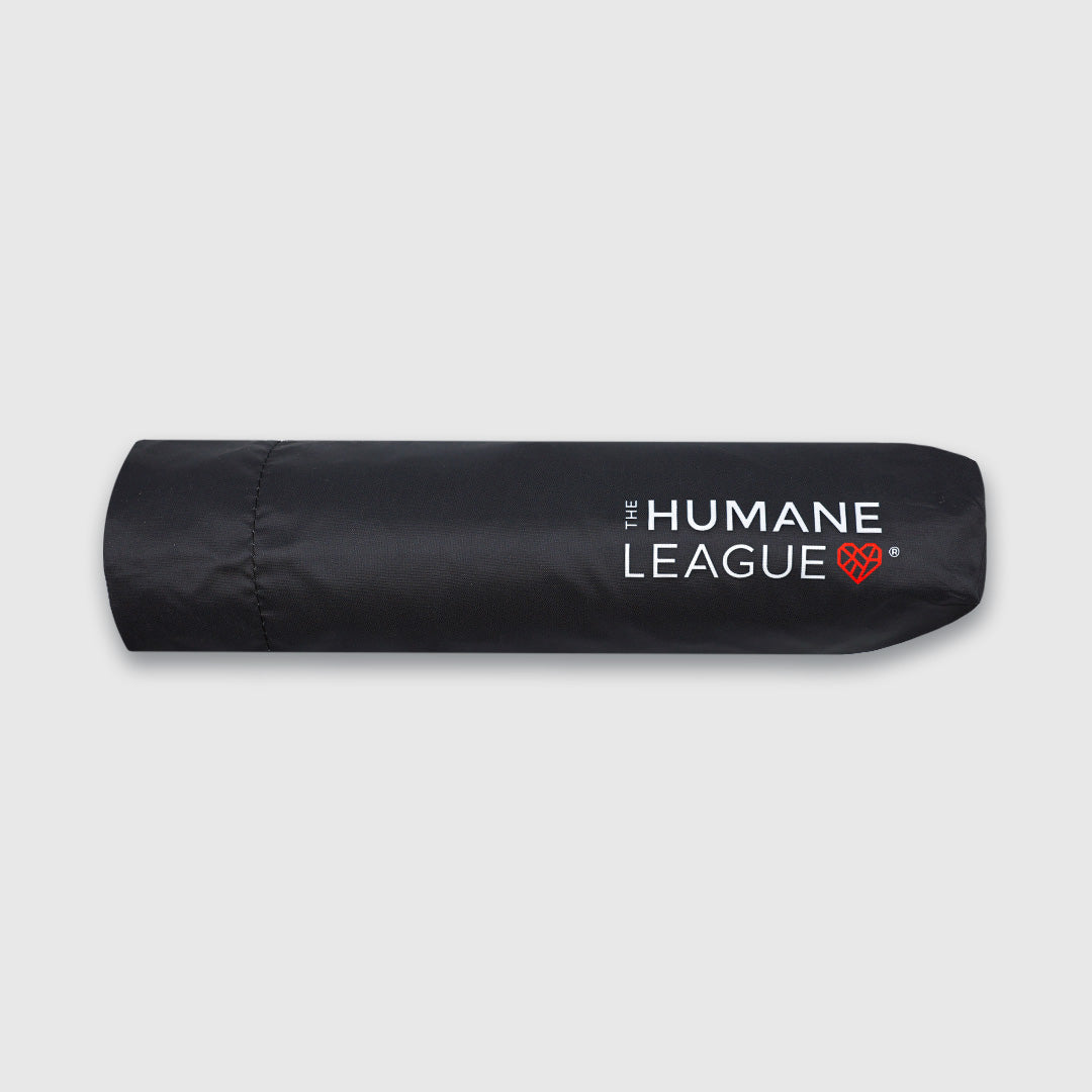 A black umbrella cover or sleeve with white text 'THE HUMANE LEAGUE' and a small red heart logo.