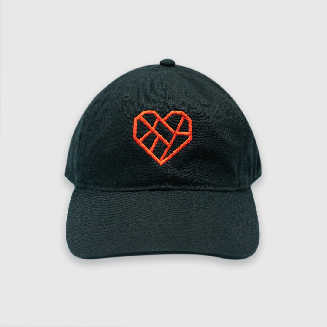 A black baseball cap with a red geometric heart design embroidered on the front. The heart design is composed of angular lines forming an abstract, lattice-like pattern. The cap has a classic six-panel structure with a curved brim, photographed against a white background.