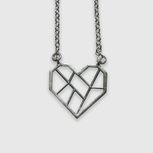 Silver pendant in the shape of a heart, with a geometric design featuring clean, angular lines that divide the heart into multiple sections. The pendant hangs from a silver, textured chain. The overall style is minimalist and modern.