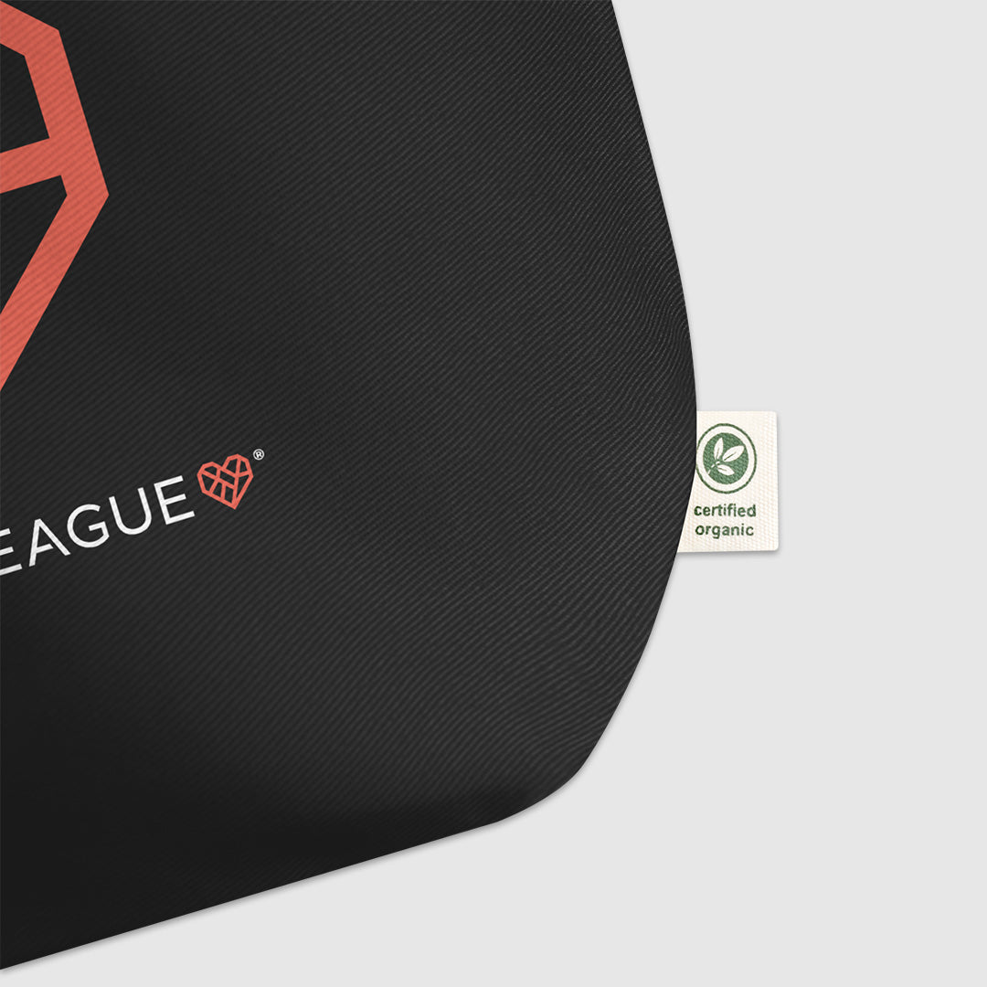 The lower right hand corner of the black tote bag showing a small beige fabric tag that says, "Certified Organic".