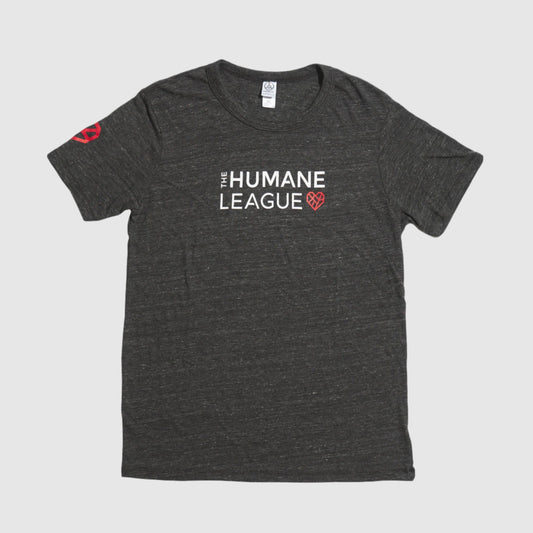 A dark gray heather t-shirt with "THE HUMANE LEAGUE" printed in white, using an all-caps font across the chest. Next to the text is a red geometric heart icon. The shirt also features the same heart icon on the wearer's right sleeve. 