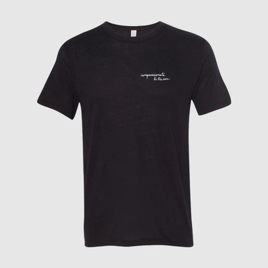 Black short sleeve t-shirt with "compassionate to the core" printed in white script on the chest on the wearer's left side.