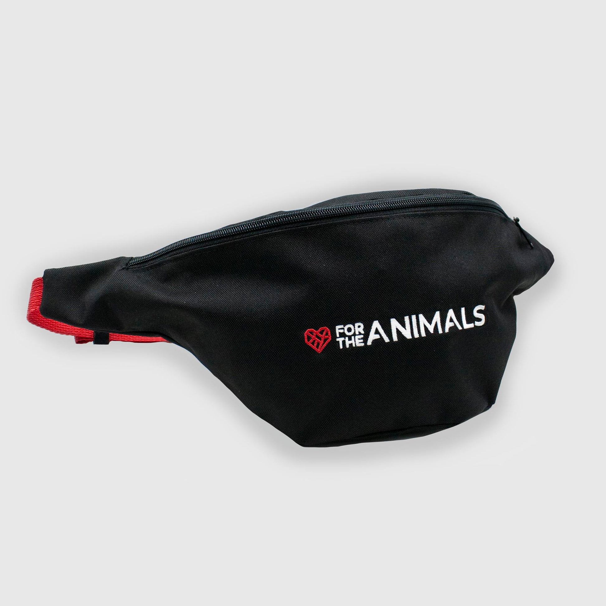 A black fanny pack with red straps. The fanny pack features the slogan "For the Animals" in white text with a small red geometric heart icon embroidered on the front.