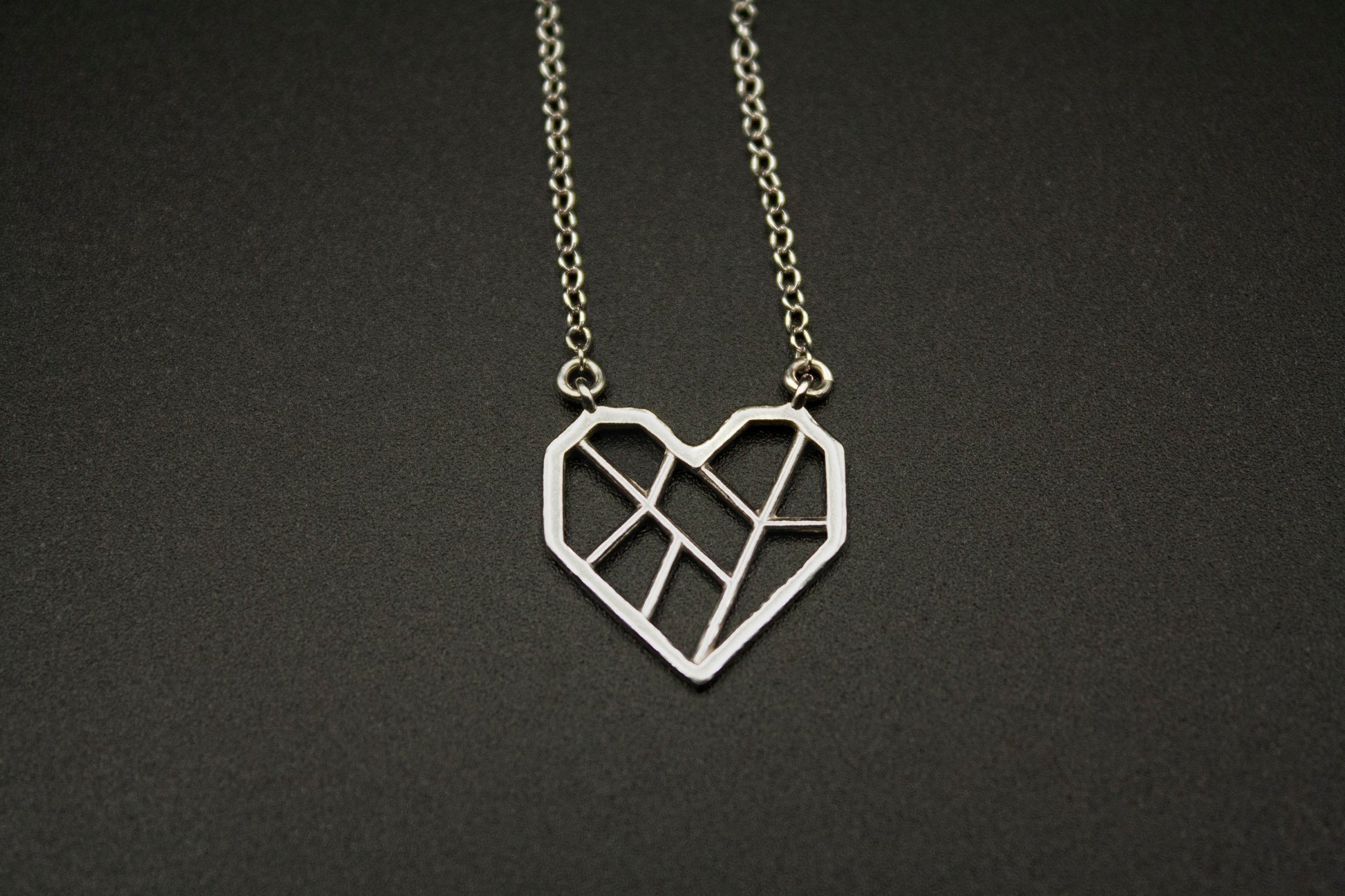 Photograph of the silver necklace against a black background.