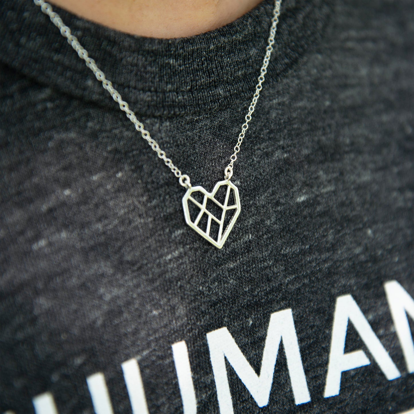 Side view of a person wearing the necklace with a dark great Humane League t-shirt.