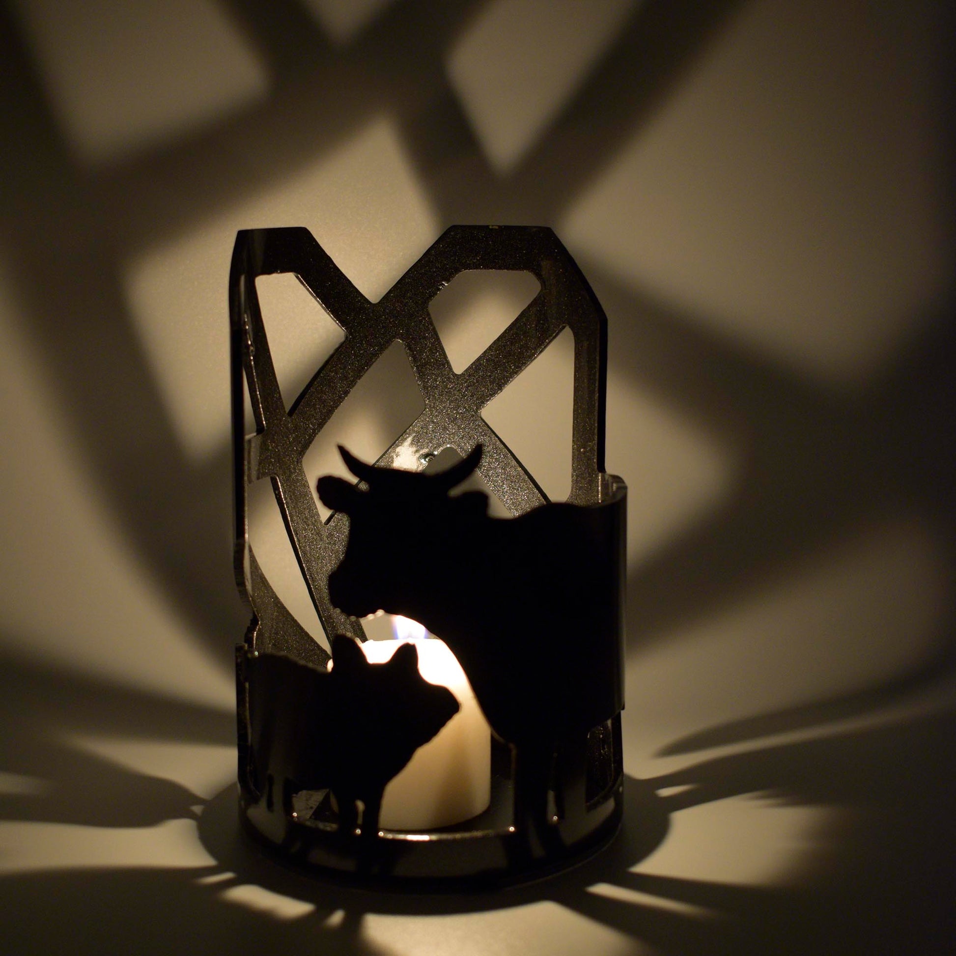 Luminary positioned showing pig and cow silouettes lit by a small candle to cast shadows of animals and Mended Heart.