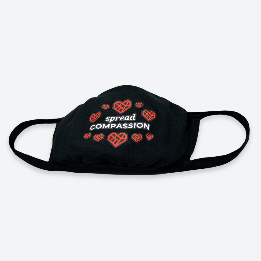 Black face mask with a design on the front featuring ten red hearts and the text "Spread Compassion" in the middle of the the circle of hearts.